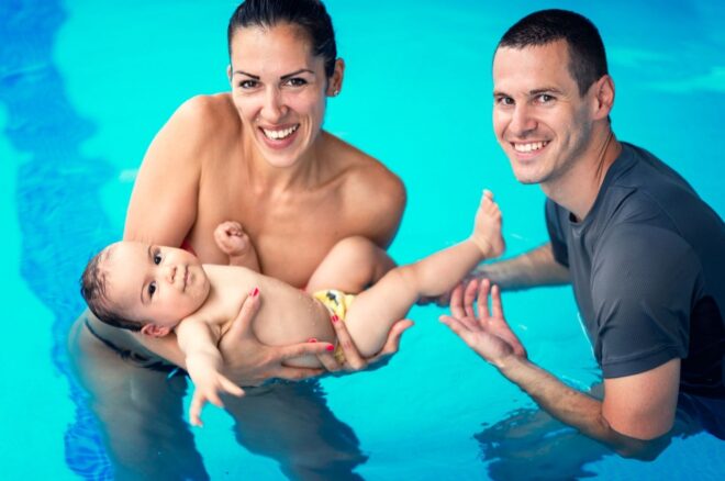 mom and dad with baby in pool