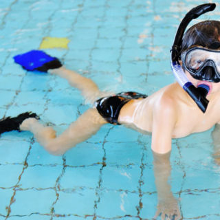 boy swims on shallow