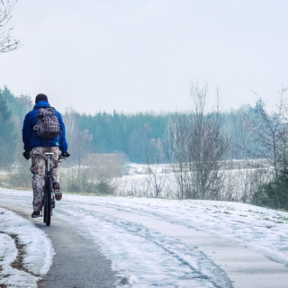 A man cycling away in snow