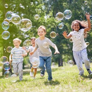 Kids run after bubbles outside summer