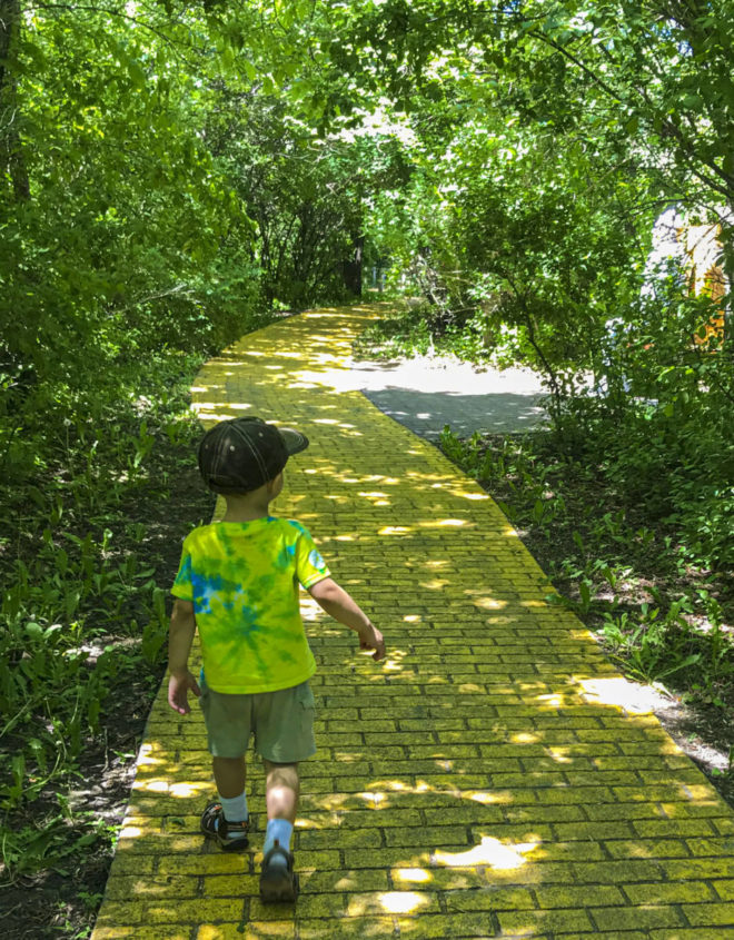 Boy walks down the yellow brick road at Land of Oz in Storybook Land Aberdeen South Dakota