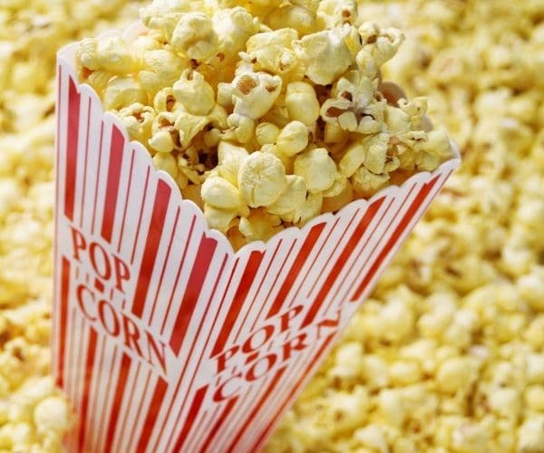 A theater popcorn box surrounded by more corn