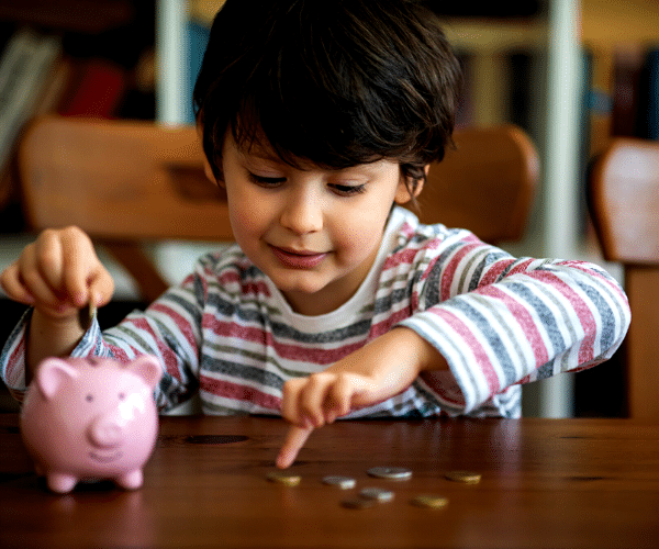 Child putting coin into piggy bank